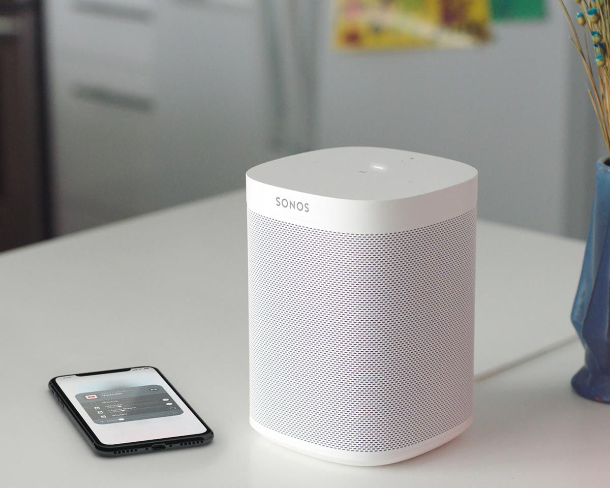 sonos smart speaker next to a smartphone with the sonos app
